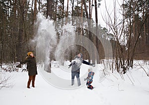 Three happy people, man, woman, child, in warm clothes, have fun playing outdoors in winter in park