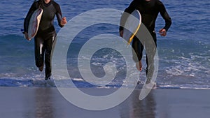 Three happy surfers running out of the sea