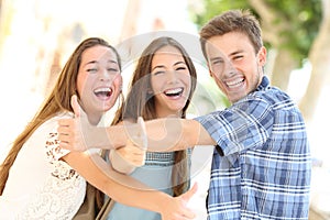 Three happy teenagers laughing with thumbs up