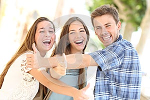 Three happy teenagers laughing with thumbs up photo