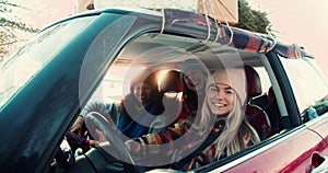 Three happy young excited multiethnic women posing, smiling at camera in fancy red car on snowy winter road slow motion.