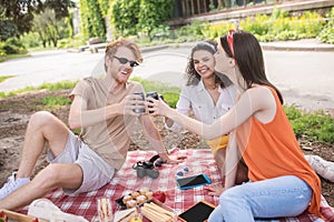 Three happy young friends having picnic in park