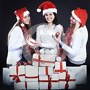 Three happy young girls dressed as Santa Claus sitting with a bu