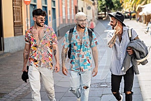 Three happy young men walking in the city, talking to each other, having fun. Multiethnic group of friends