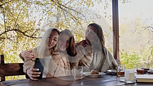 Three happy young women takes a selfie on phone in terrace together