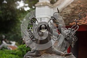 Three headed dragon made of bronze with glass ball in their mouth on the top of the antique incense burner at Temple of Literature