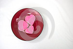 Three heart shaped cookies arranged on red plate