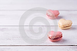 Three heart shaped, cream filled French Macaroons on white wooden Background. Confectionery for Valentine\'s Day,