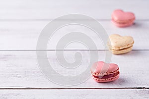 Three heart shaped, cream filled French Macaroons on white wooden Background. Traditional confectionery for Valentine\'s Day,