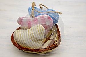 Three hearts, sewn from scraps of cloth and tied with coarse thread, in a small wicker basket, on a light wooden background