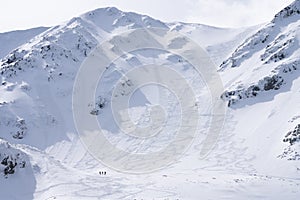 Three hikers during winter standing at the bottom of snowy mountain , Slovakia, Europe