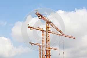 Three hoisting cranes with pulley and hook in construction site