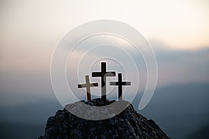 The three holy crosses of Jesus Christ shining through the red sky and clouds and bright rays background. Silhouette cross on