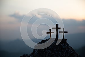 The three holy crosses of Jesus Christ shining through the red sky and clouds and bright rays background. Silhouette cross on