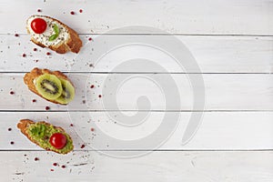 Three homemade mini sandwiches on white wooden background, top view, copy space