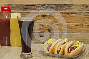 Three hot dogs and a glass with cola drink