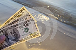 Three hundred dollar bills on background of sea surface. 100 dollar cash