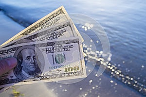 Three hundred dollar bills on background of sea surface. 100 dollar cash