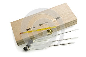 Three hydrometers for measuring degree of alcohol and thermometer in white background