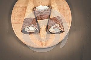 three ice cream with cone in chocolate/three ice cream with cone in chocolate on a round wooden support, top view