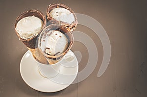 three ice cream with cone in chocolate on a in a white cup/three ice cream with cone in chocolate on a in a white cup on a dark