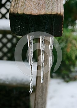 Three icicles hang from a hand rail of a stair