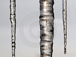 Three icicles vertically on the background of cloudy sky.