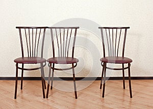 Three identical chair next against the wall