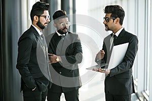 Three indian business at meeting discuss the plans on laptop working together at modern office