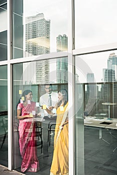 Indian employees sticking reminders on glass wall in the office