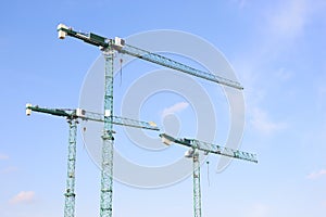 Three industrial construction tower cranes.