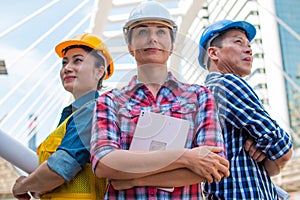 Three Industrial engineer wear safety helmet engineering standing with arms crossed on building outside.