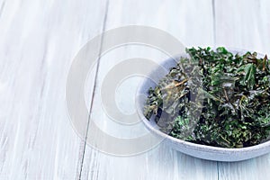 Three ingredient baked green kale chips with sea salt and olive oil, in gray bowl, horizontal, copy space