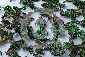 Three ingredient baked green kale chips with sea salt and olive oil, on parchment, horizontal