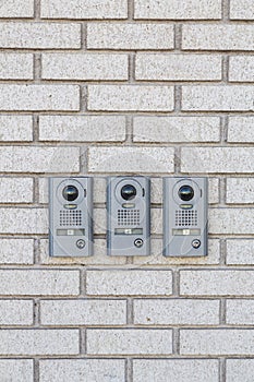 Three intercom on white textured brick wall, Close up