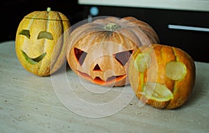 Three jack-o`-lanterns from pumpkin and melons on kitchen table.