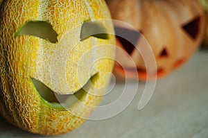 Three jack-o`-lanterns from pumpkin and melons on kitchen table.