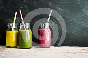 Three jars of fruit colorful drinks with straws