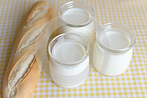 Three jars with Greek yoghurt and a crispy French baguette