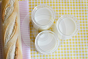 Three jars with Greek yoghurt and a crispy French baguette