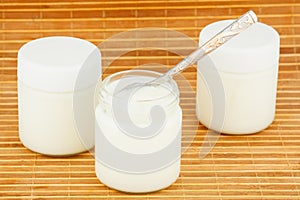 Three jars with home yoghurt on a straw mat