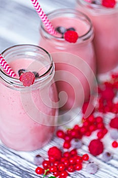 Three jars with yogurt smoothie with cranberry, raspberry, blueberry on wood table. Selective focus