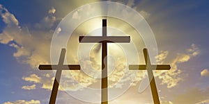 Three Jesus Christ christian crucifixes or crosses backlit from sunset or sunrise sky with glowing rays, god, resurrection, easter