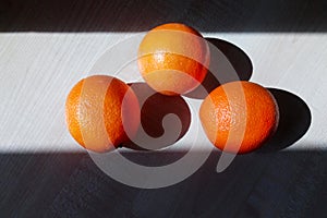 Three juicy oranges lie on a wooden table