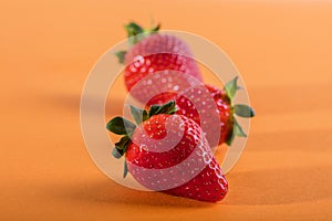 Three juicy strawberry on orange background