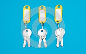 Three keys pair on yellow keychains blue background photo