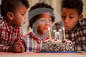 Three kids blowing candles out.