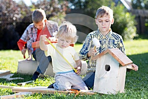 Three kids boys brothers making wooden birdhouse by hands