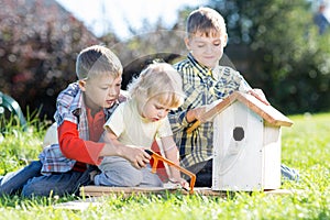 Three kids boys brothers making wooden birdhouse by hands