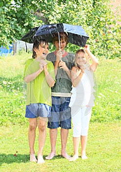 Three kids with broken black umbrella